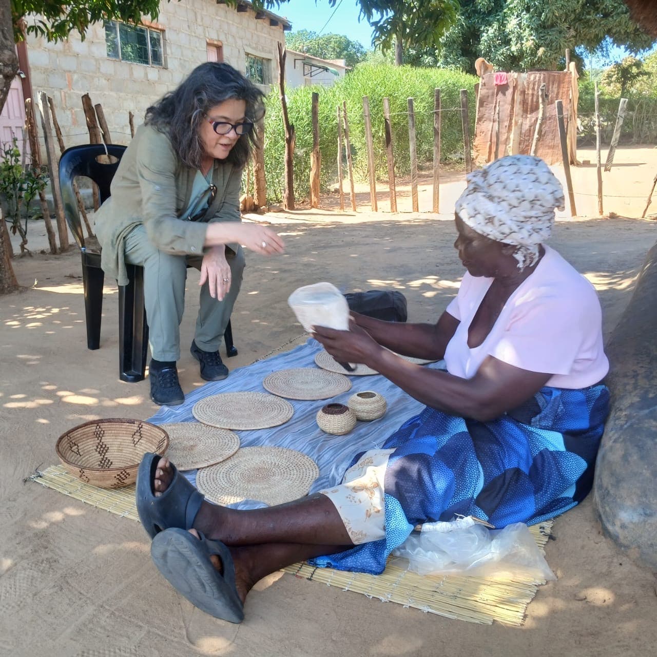 A visitor talking with a basket maker beside her woven pieces